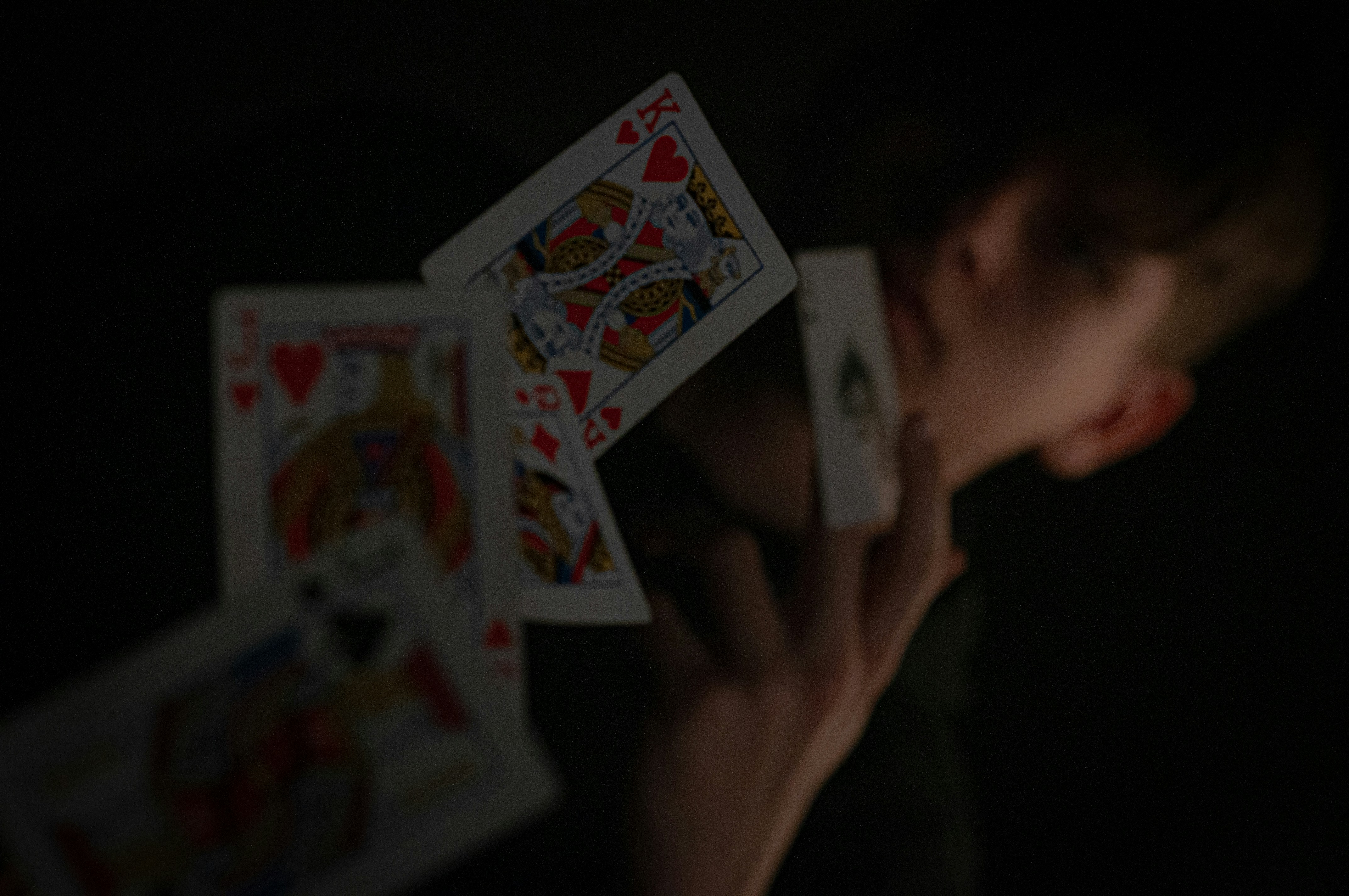 a person holding up playing cards in the dark