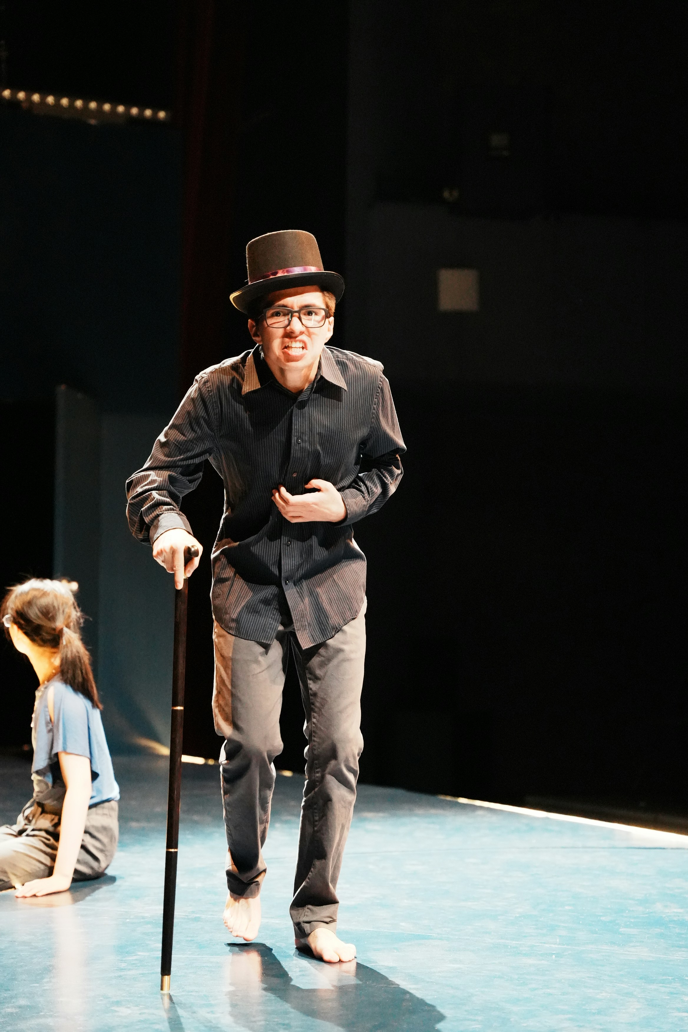 A man standing on a stage holding a cane