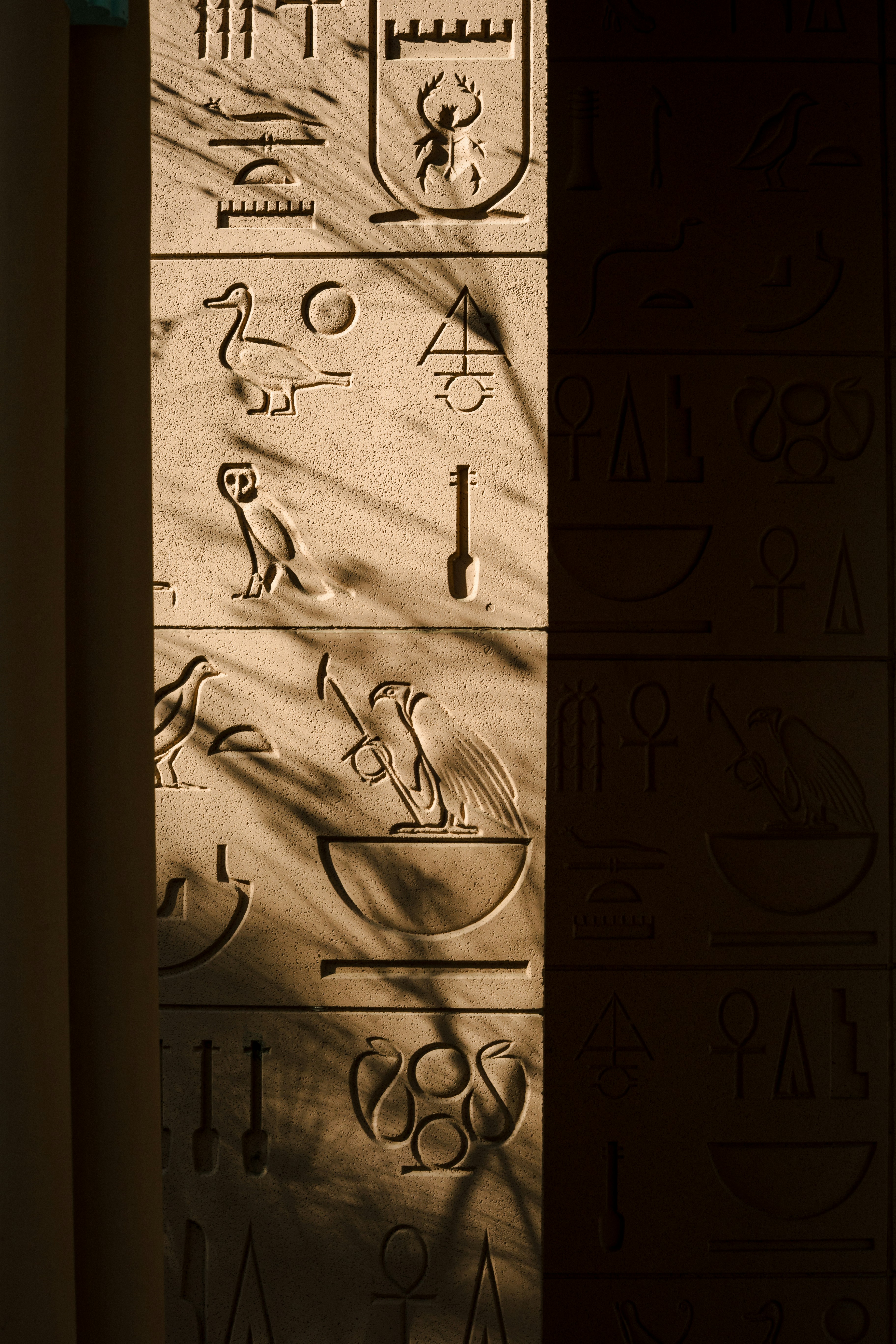 Egyptian hieroglyphs carved into stone with shadows.
