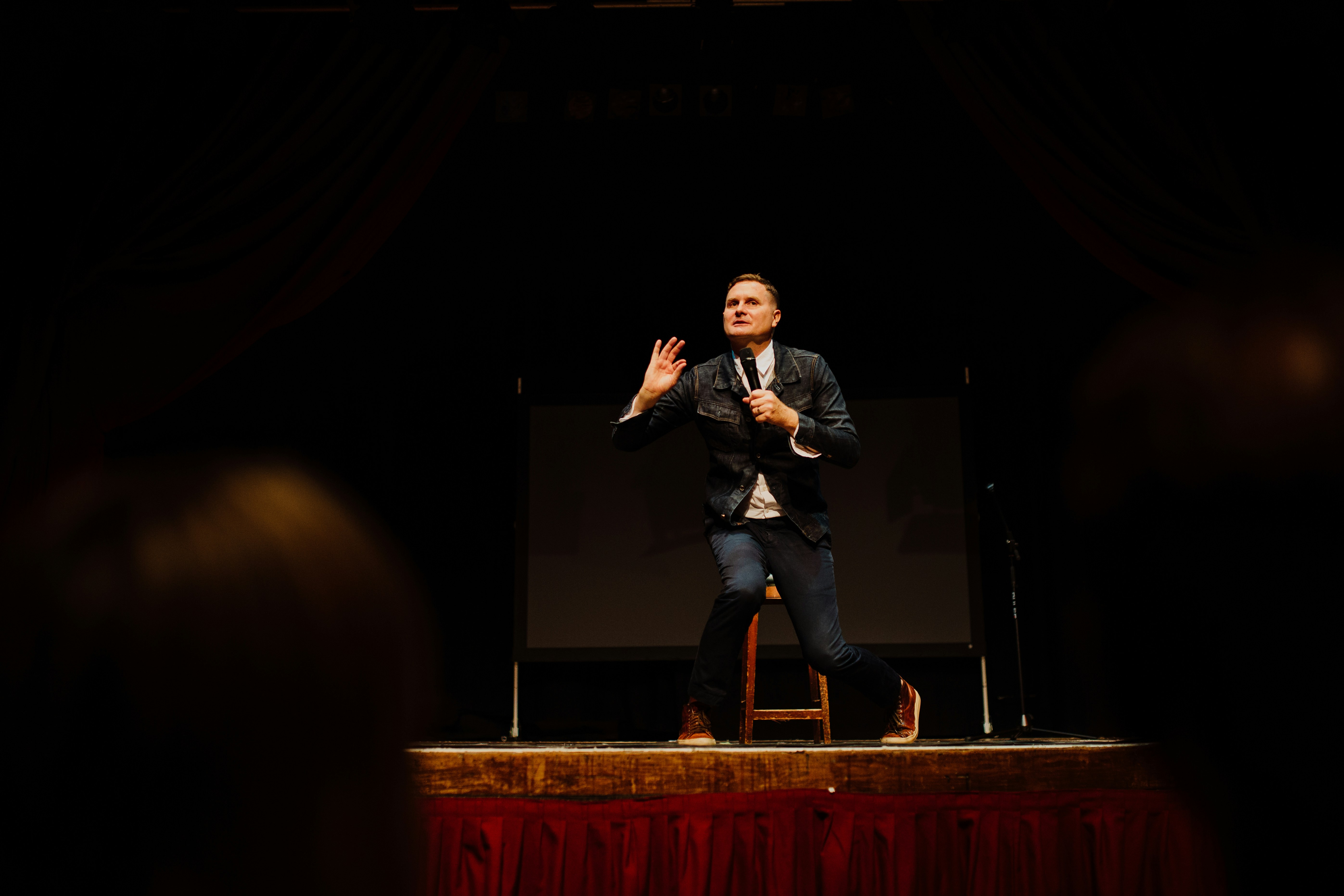man in black suit singing on stage