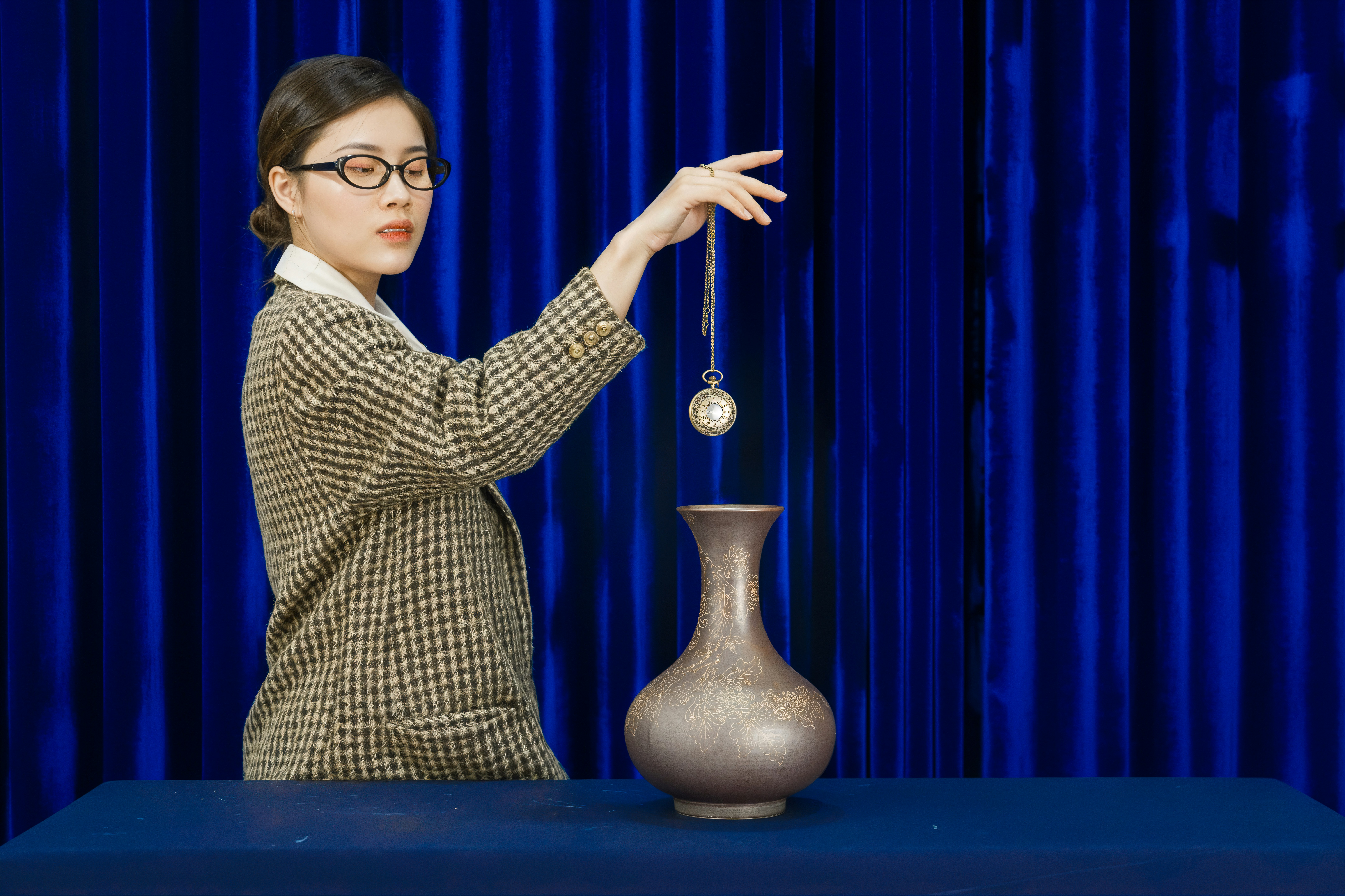 Woman with glasses dangles pendulum over vase