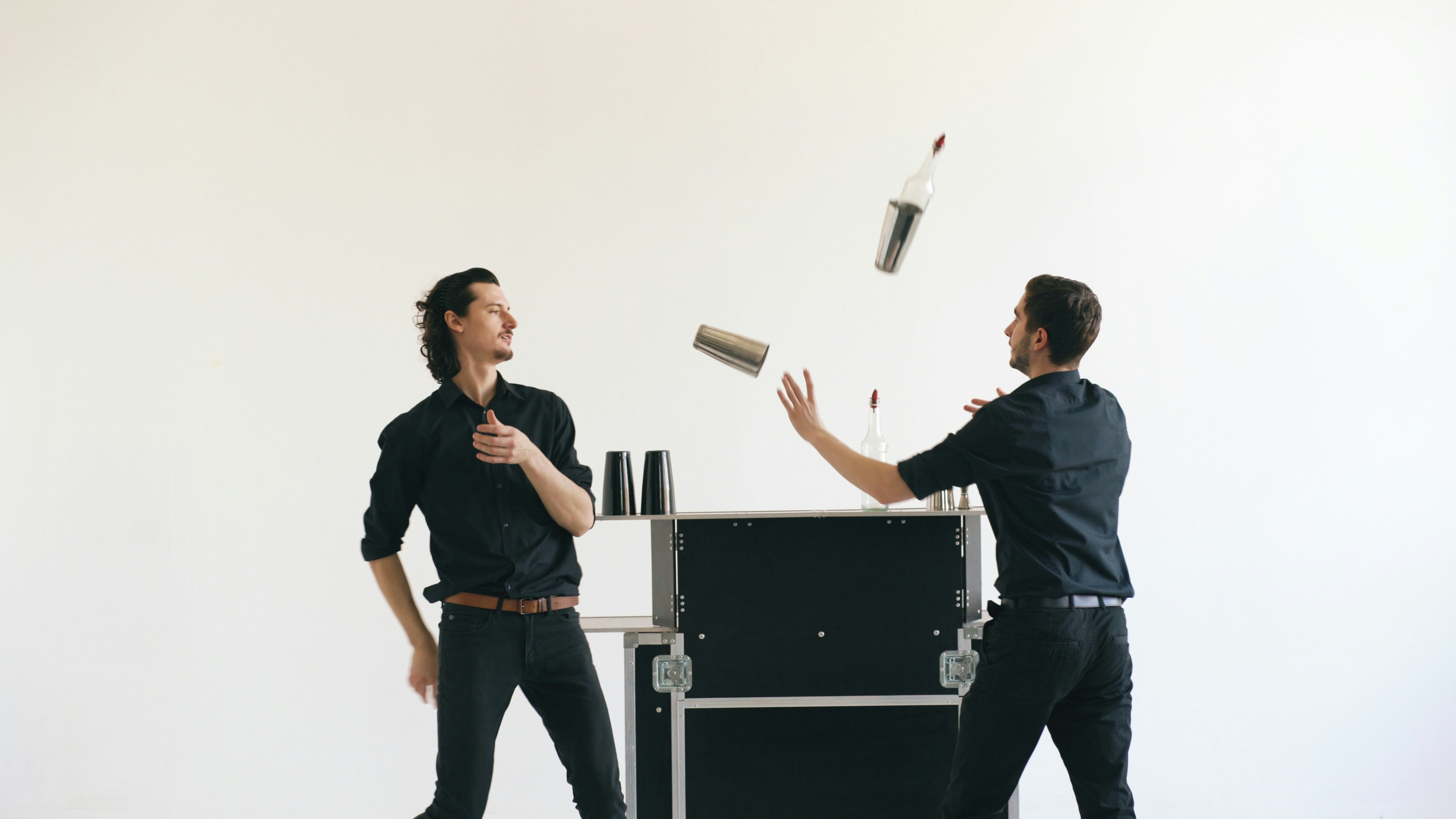 Two bartenders juggling bottles and shakers