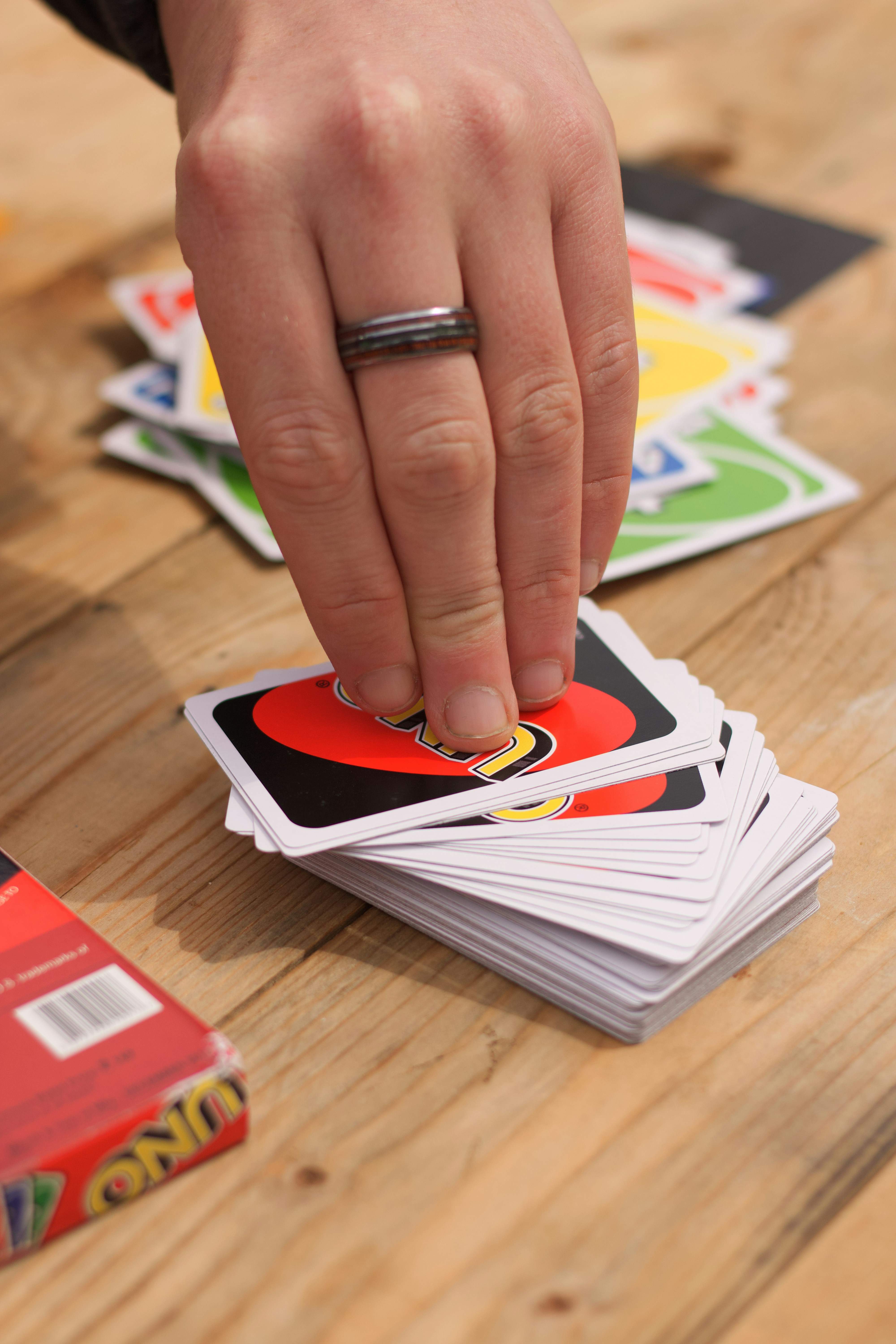 Uno card being picked off the deck. by Magic Trick person wearing silver ring holding white and red book