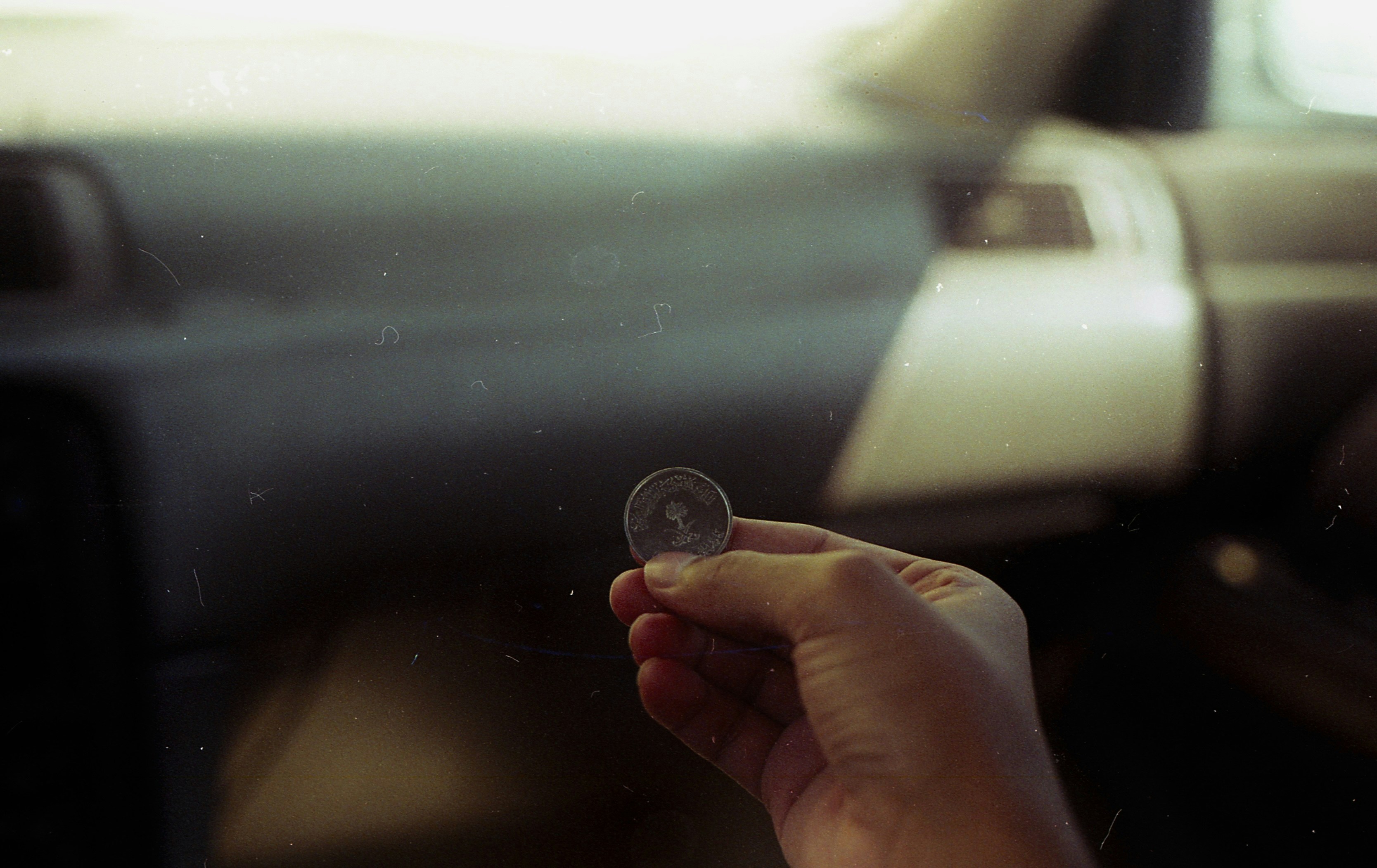 A person holding a glass in their hand while driving a car