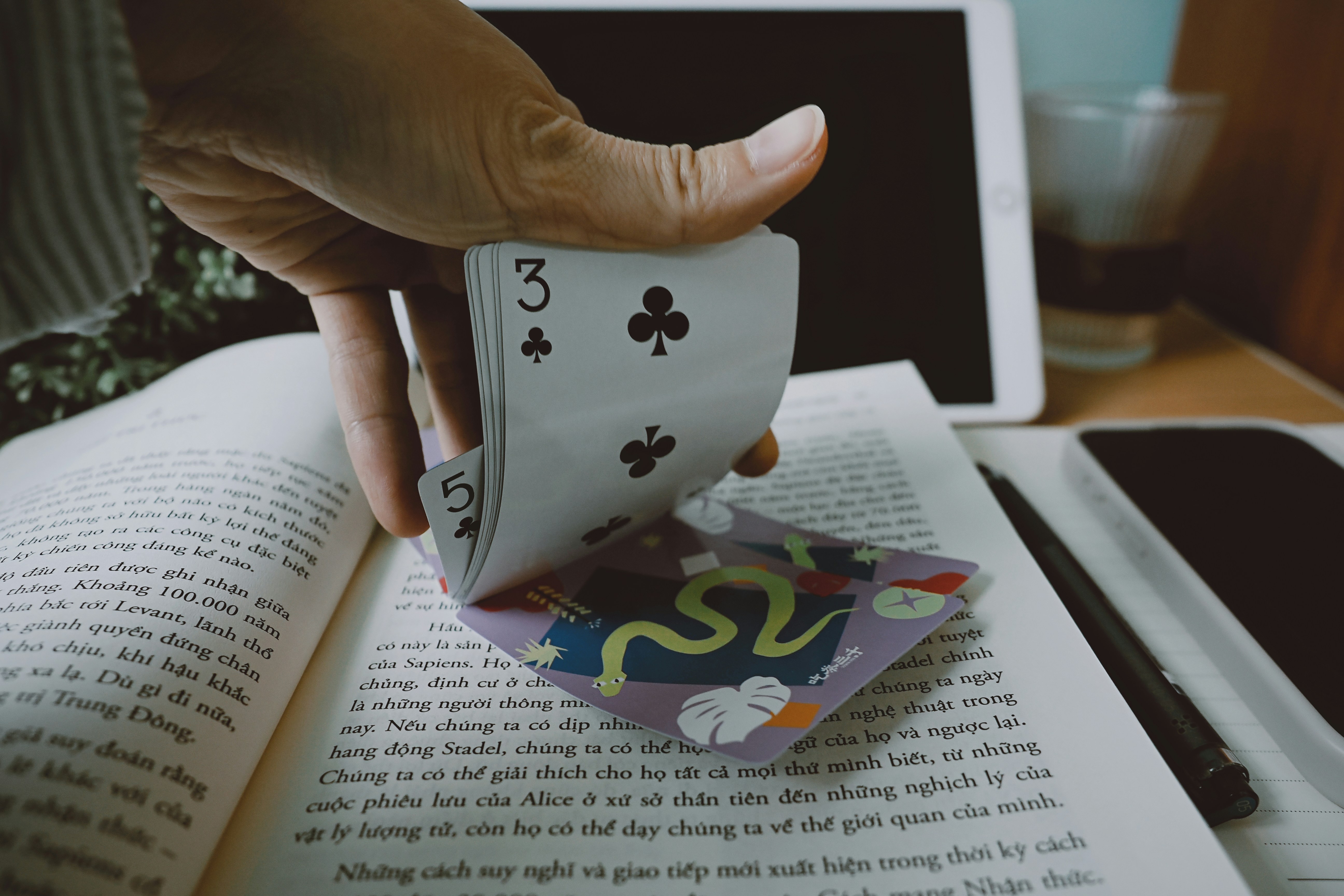 ❓ FAQ by Magic Trick Hand holding a playing card over an open book