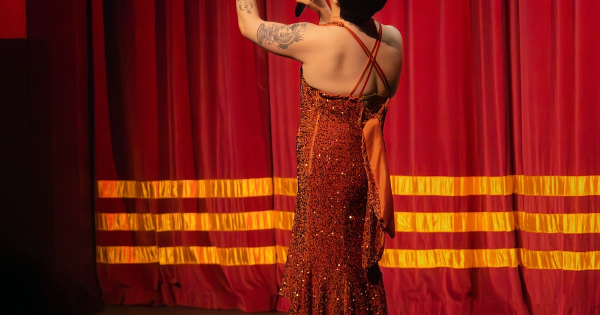 Magic Trick by Magic Trick Performer on stage in a sparkly dress holding cards